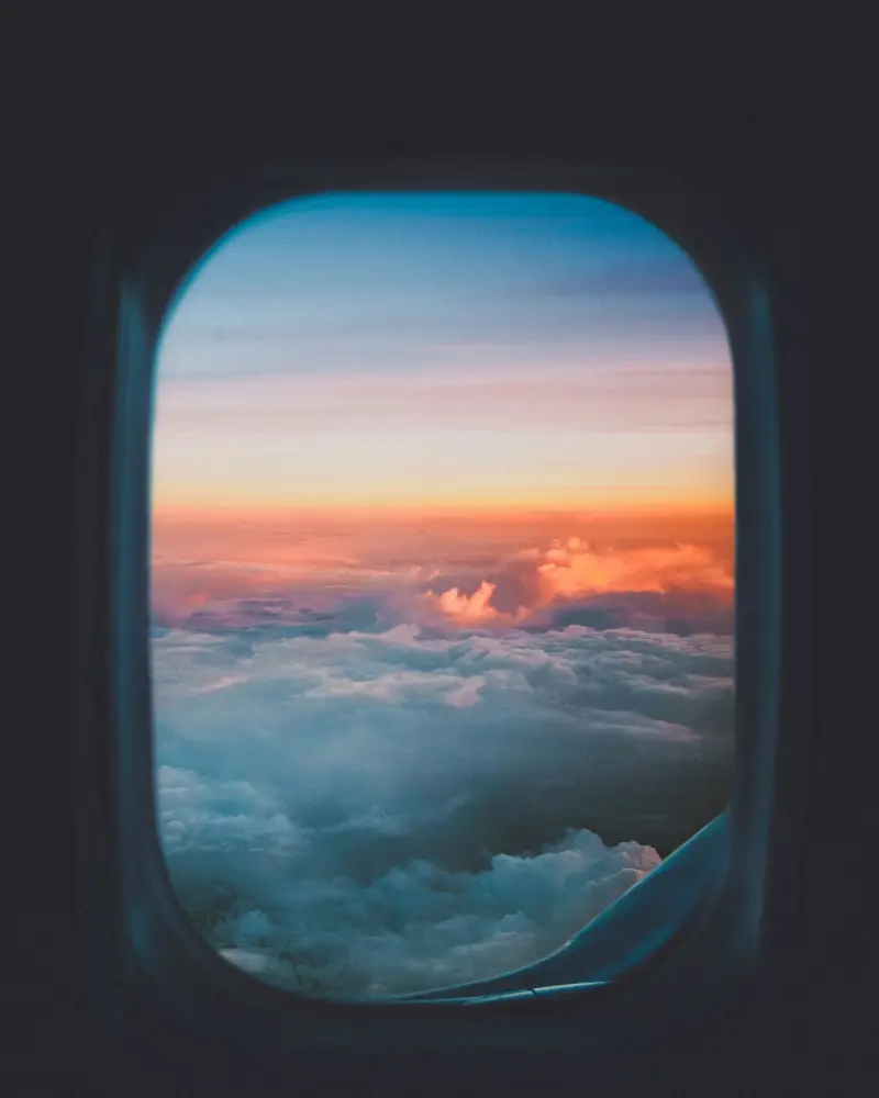 View of clouds at sunset through an aircraft window