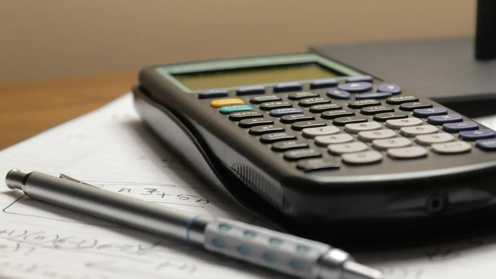 A calculator and a pen resting on handwritten notes